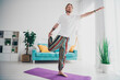 © deagreez - Full size photo of nice young man stretching leg yoga pose wear stylish pajama modern light cozy interior flat indoors