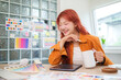 © wattana - Cheerful graphic designer with long red hair is enjoying her work in a creative workspace.