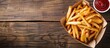 © StockKing - Horizontal picture of French fries served on a wooden table with sauce, creating a copy space image.