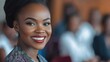 © Miftahul - Professional African woman with a radiant smile engages attendees as she speaks at a business conference. With a blurred team in the backdrop, she embodies leadership and confidence.