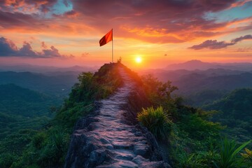 Wall Mural - A stunning sunset view from a rocky peak, with a flag gently waving against a vibrant sky and lush mountains in the background