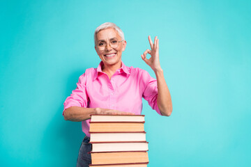 Wall Mural - Portrait of nice aged lady okey symbol book wear pink shirt isolated on turquoise color background