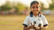 © Niks Ads - south indian school girl in her uniform holding a soccer ball in her arm, dirt from mud after the soccer game on her uniform.