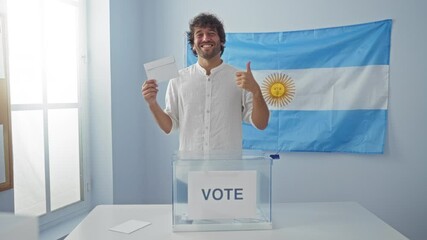 Wall Mural - Young hispanic man holding vote sign, smiling and positive, showing approval at argentinian electoral college, happy and confident