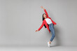 © New Africa - Cheerful woman in red jacket and jeans on gray background, space for text