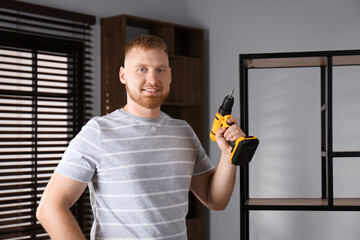 Wall Mural - Man with electric screwdriver at home. Assembling furniture