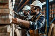 © jureephorn - A seriously handsome bearded worker of a furniture factory wears safety glasses looking at wood panels. making furniture
