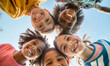 © IBEX.Media - A group of happy, diverse children huddled in a circle, looking down and smiling at the camera, representing unity, friendship, and multicultural togetherness