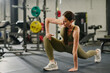 © AnnaStills - Toned female athlete practicing static stretching in fully equipped gym