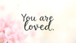 © Tark - “You Are Loved” text in a sweet, hand-lettered font with a soft floral background. Generative AI