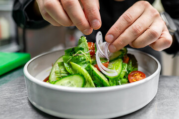 Sticker - A close-up of hands garnishing a fresh salad with onion rings, highlighting the vibrant colors and textures of the ingredients. Perfect for healthy eating, culinary blogs, and food-related content.