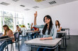 © Mediteraneo - Female student raising her hand in class to ask some question