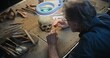 © Framestock - Mature archaeologist cleans fossil skull under lamp using professional tools and brush. Scientist studies remains of extinct prehistoric human, works in archaeological laboratory. Close Up. Zoom In.