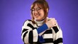 © Robert Peak - Portrait of young woman wearing glasses and sweater 20s with sore neck shoulder pain problem isolated on purple background in studio