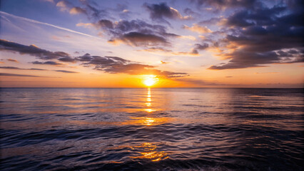 Wall Mural - A beautiful sunset over a calm ocean with the sun dipping below the Horizon