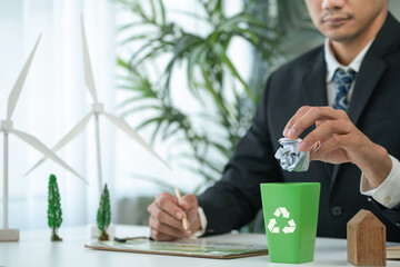 Wall Mural - Businessman put paper waste on small tiny recycle bin in his office symbolize corporate effort on eco-friendly waste management by recycling for greener environment and zero pollution. Gyre