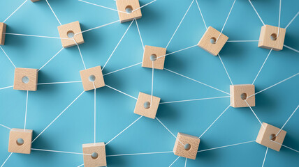 Abstract social network concept with wooden blocks connected by white strings on a blue background, top view. 