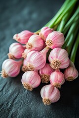 Wall Mural - Fresh pink garlic bulbs stacked on a dark stone surface