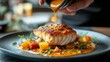 © olegganko - Chef drizzling sauce over a beautifully plated fish dish in a fine dining restaurant