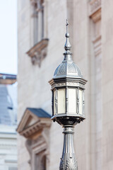 Sticker -  Light is tall and has a decorative top. Street light on a pole illuminates the area in front of a building, enhancing the urban landscape