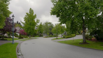 Wall Mural - Establishing shot of two story stucco luxury house with big tree and nice landscape at spring rainfall in Vancouver, Canada, North America. Day time on June 2024. ProRes 422 HQ.