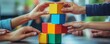 © saichon - Hands of diverse people stacking blocks to build a tower, representing teamwork and cooperation