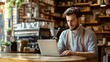 © Jardel Bassi - Trendy Coffee Shop Interior: Young Entrepreneur Working on Laptop