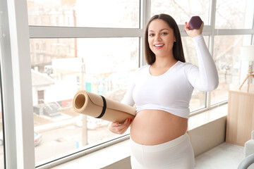 Canvas Print - Sporty pregnant woman with fitness mat and dumbbell at home