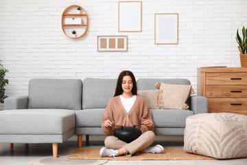 Canvas Print - Young woman playing glucophone on floor near sofa in living room