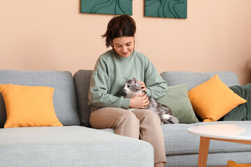 Poster - Young woman with cute longhaired cat sitting on sofa in living room