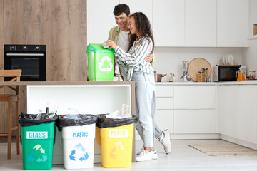 Sticker - Young couple throwing can into garbage container in kitchen. Waste sorting concept