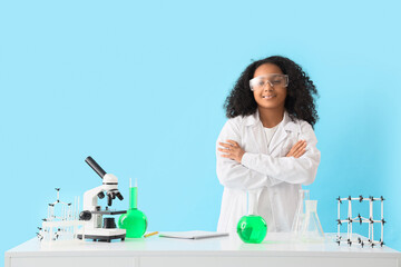 Canvas Print - Little African-American schoolgirl with chemical flasks at table on blue background