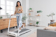 © Pixel-Shot - Young businesswoman with tablet computer training on treadmill at home