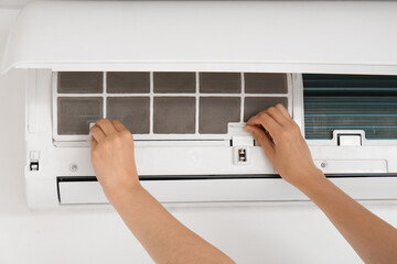 Female technician changing dirty air conditioner filter at home, closeup