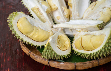 An opened durians arranging on wooden tray. Durian is a delicious tropical fruit native to Southeast Asia and is widely known as the “King of Fruits”.