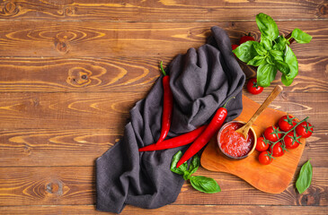 Poster - Bowl of tomato sauce with basil and chili peppers on wooden background