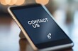 © nabila - Close-up of a smartphone screen displaying the words CONTACT US on a phone screen, communication theme, copy space