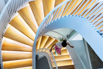 Wall Mural - Woman walking on spiral staircase