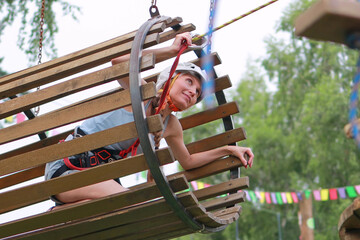 Wall Mural - woman in equipment goes through obstacles in rope park