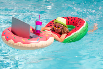 Wall Mural - Summer travel and business concept. Kid remote working on laptop in pool. Little business man working online on laptop in summer swimming pool water.