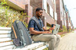 © unai - African man working with laptop sitting on a city bench