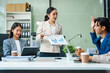 © Phushutter - In a boardroom, an Asian team meets at a desk, presenting financial terms and strategies. Executives and employees collaborate, sharing ideas and work guidelines for success during an annual meeting.