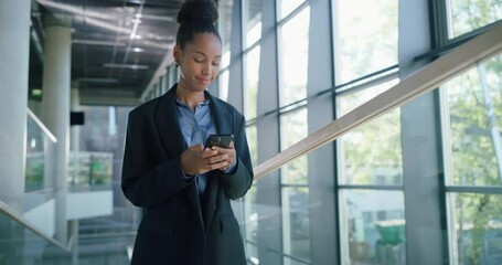 Poster - African Female Professional Walking Through a Modern Office Hall, Using Her Smartphone for Browsing Online. Young Woman Connected to the News, Social Network Data and Internet Applications