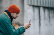 © carballo - portrait of young man with hat and warm clothes looking at mobile phone