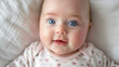 © Mutshino_Artwork - Portrait of a Smiling Baby with Big Blue Eyes on a Soft White Blanket