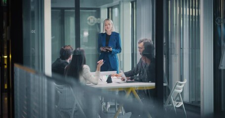 Aufkleber - Young Female Manager Hosting a Meeting with a Team. Advisors and Partners Negotiating in the Office in a Glass Conference Room. Diverse Colleagues Sitting Behind a Table, Discussing Business