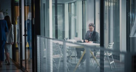 Poster - Young Businessman in a Suit Sitting Alone in His Office. Entrepreneur Working on a Laptop Computer, Communicating with Partners, Vendors and Businesspeople Online. Satisfied Manager Relaxing at Work