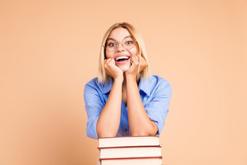 Poster - Photo of adorable impressed girl wear blue shirt reading book stack empty space isolated beige color background