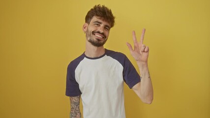 Wall Mural - Confident young hispanic man standing over isolated yellow background, smiling and happily showing number three with fingers, pointing up