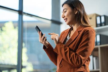 Business woman are using a mobile phone search information on the desk in the morning.